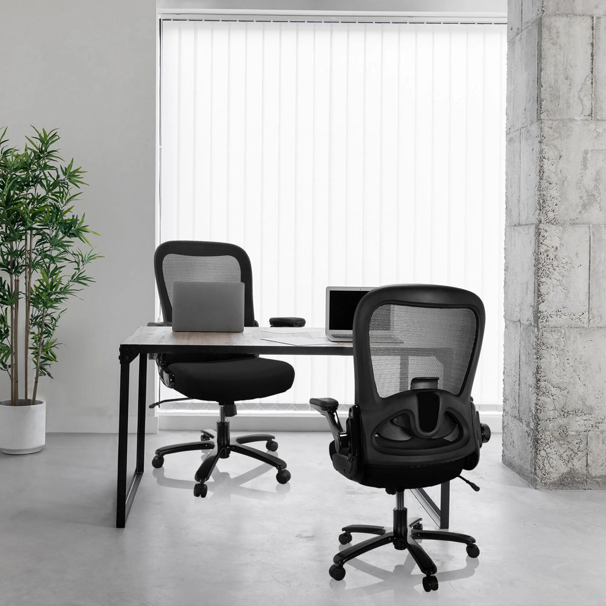 Två svarta XXL snurrstolar INSTRUCTOR SW I med nätrygg vid ett skrivbord från hjh OFFICE
