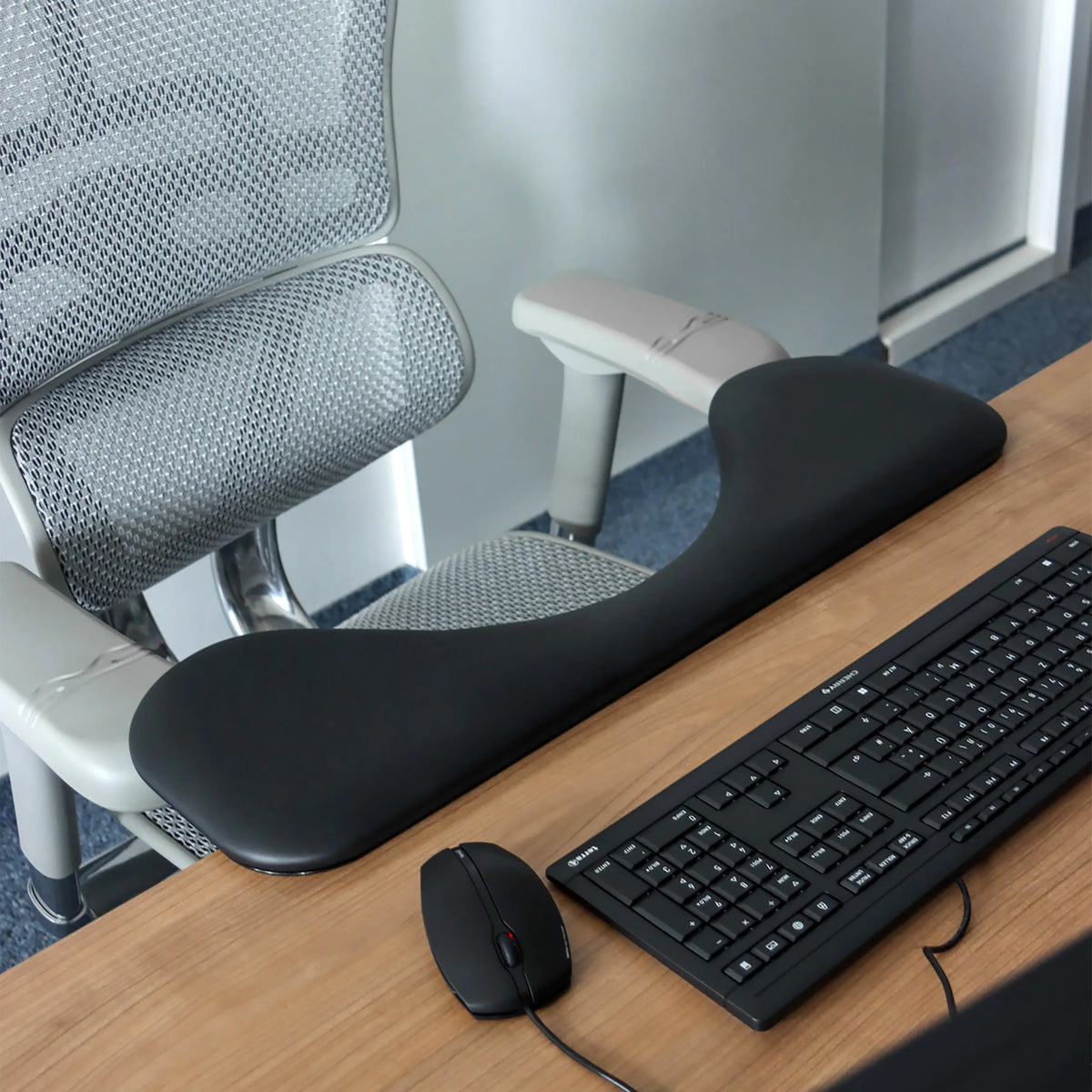 Svart RELEX RT2 armstöd på ett skrivbord bredvid ett tangentbord och en datormus från hjh OFFICE