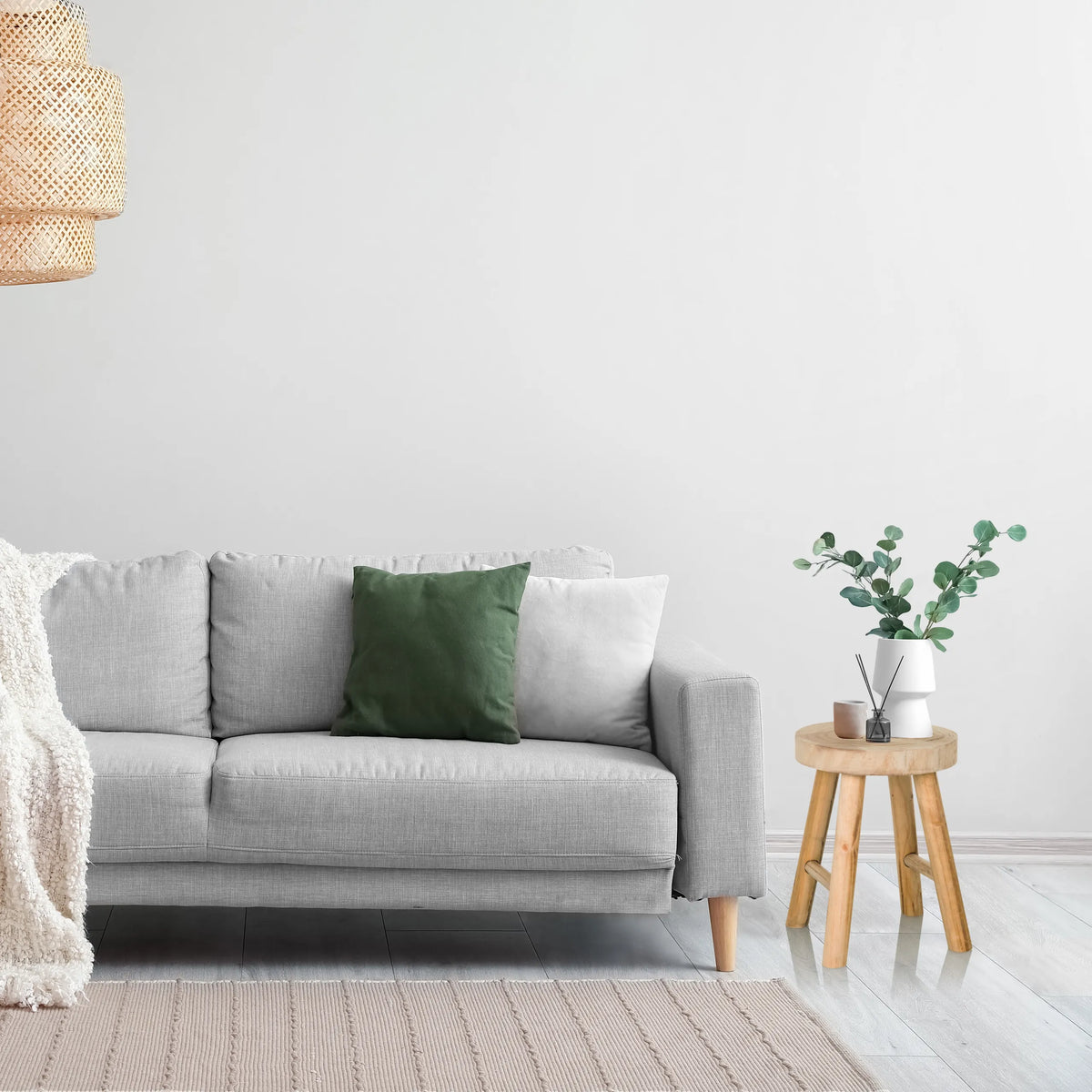 Brun sittpall i trä RUSTIKO W som sidobord bredvid en grå soffa från hjh LIVING