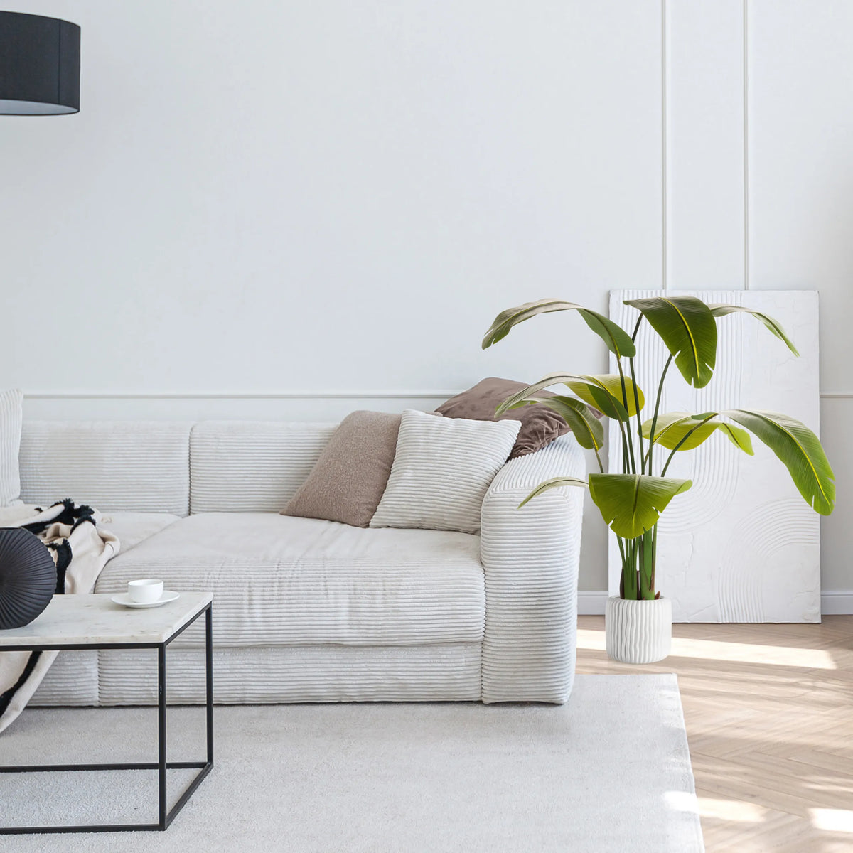 Gröna Konstgjorda växter BANANE i en vit kruka bredvid en soffa från hjh OFFICE