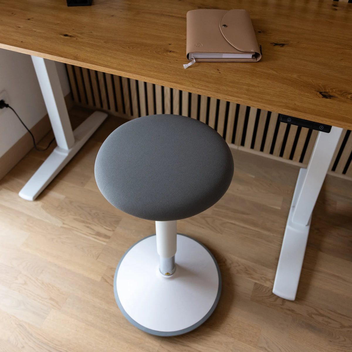 Grå stoppad sits på BALANCE SIT III W ståstol med vitt korsben och central pelare från hjh OFFICE