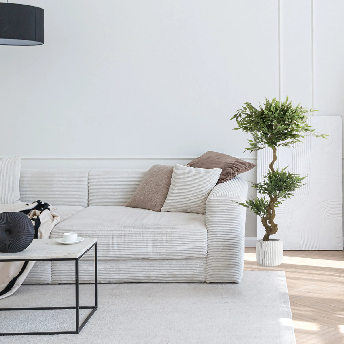 Grön konstgjord växt ACACIA i en vit kruka bredvid en soffa från hjh OFFICE