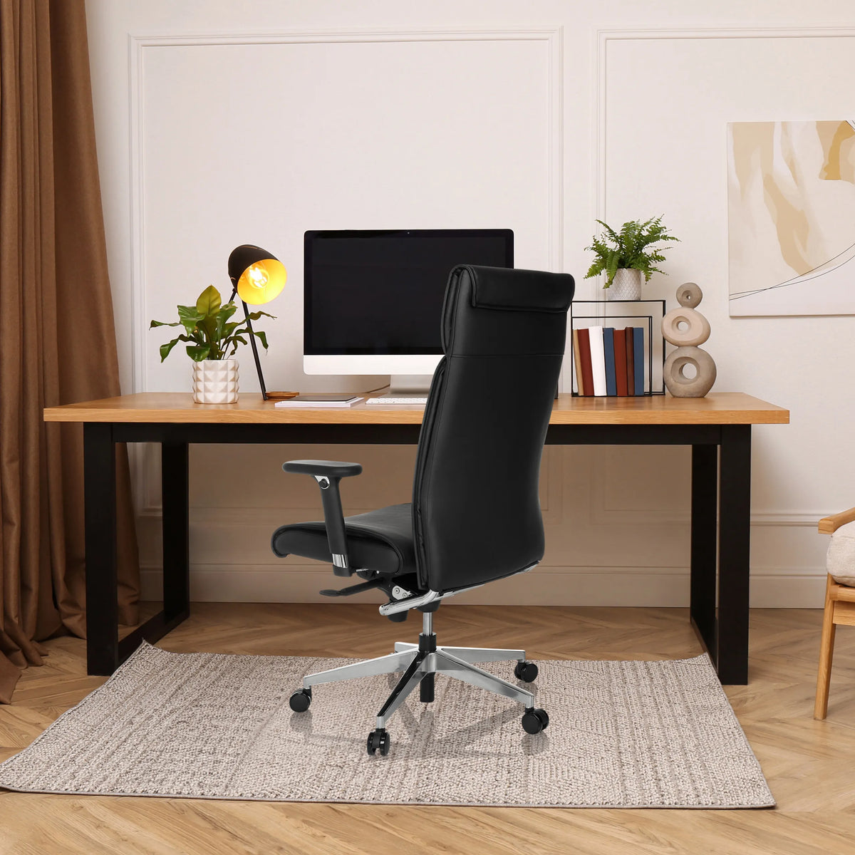 Svart professionell chefsfåtölj CURYO med nackstöd och armstöd vid ett skrivbord på ett hemmakontor från hjh OFFICE