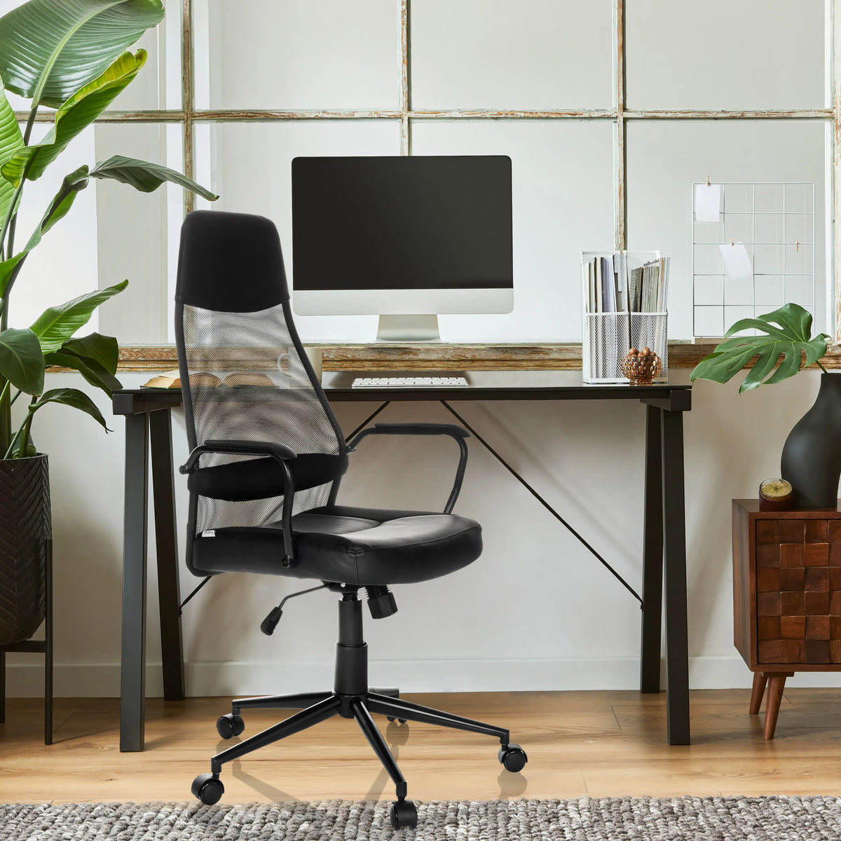 Svart MARCOZ Home Office chefsfåtölj med nätryggstöd och armstöd framför ett skrivbord från MyBuero