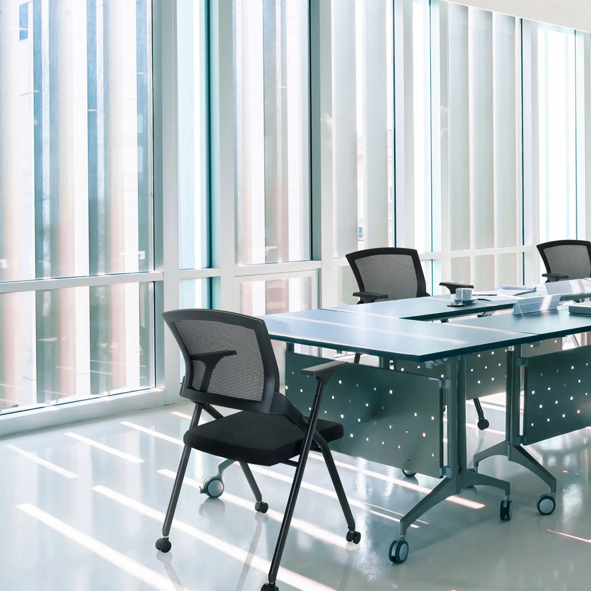 Hopfällbar stol PRIORITY II i svart med nätryggstöd vid ett konferensbord från hjh OFFICE