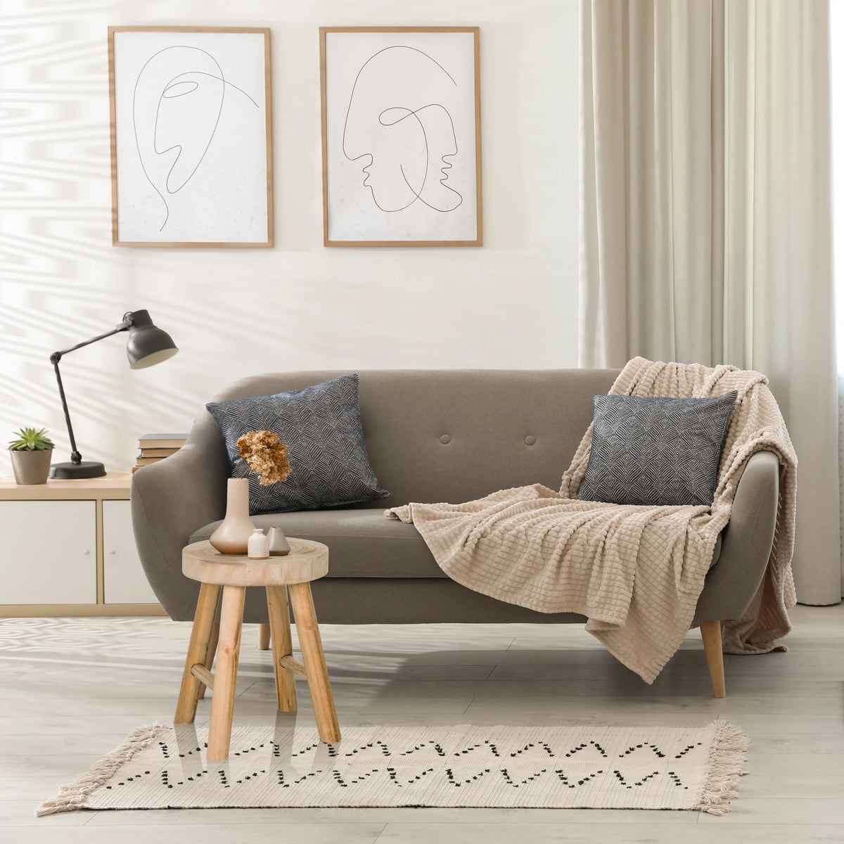 Brun RUSTIKO W sittpall i trä som sidobord framför en grå soffa från hjh LIVING