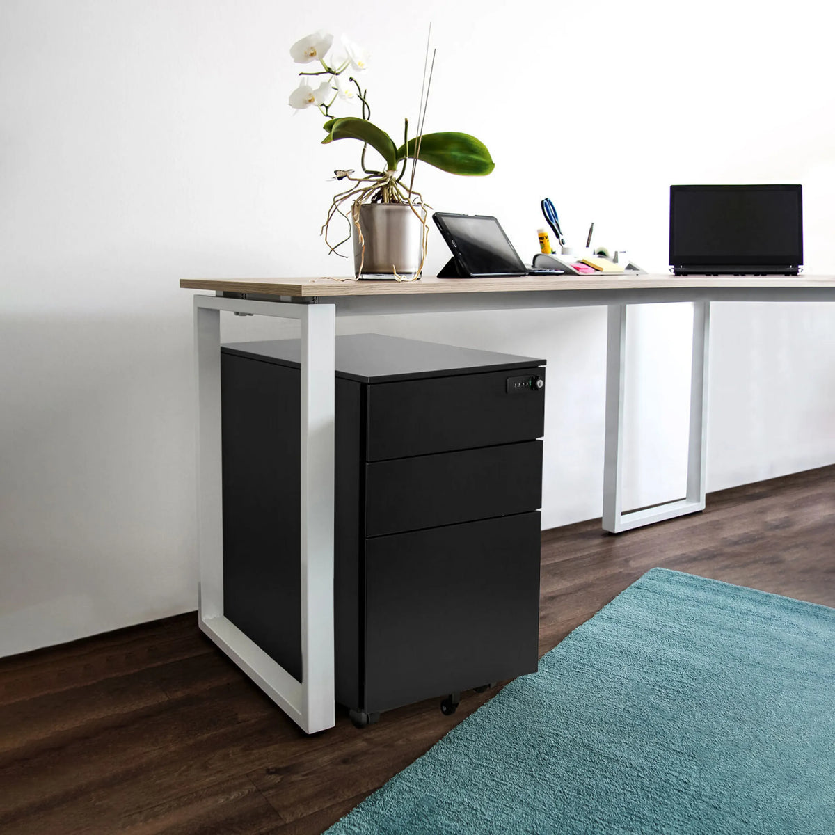 Svart rullcontainer i metall COLOR OS I under ett skrivbord med en ljus träskiva från hjh OFFICE