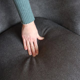 Grått tygöverdrag på sitsen av HAYRIVER loungesoffa under en hand från hjh LIVING
