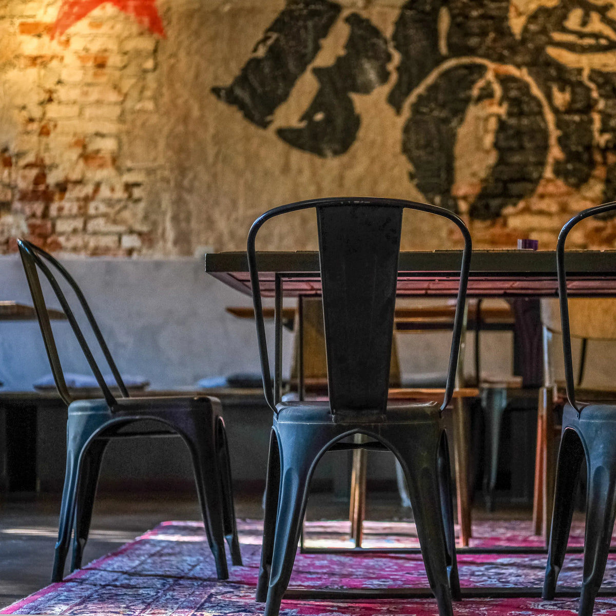 Baksidan av en svart VANTAGGIO BRUSH bistrostol i metall vid ett bord från hjh OFFICE