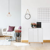 Vit byrå ESTHA med två dörrar och ljusa träben i ett ljust vardagsrum från hjh LIVING