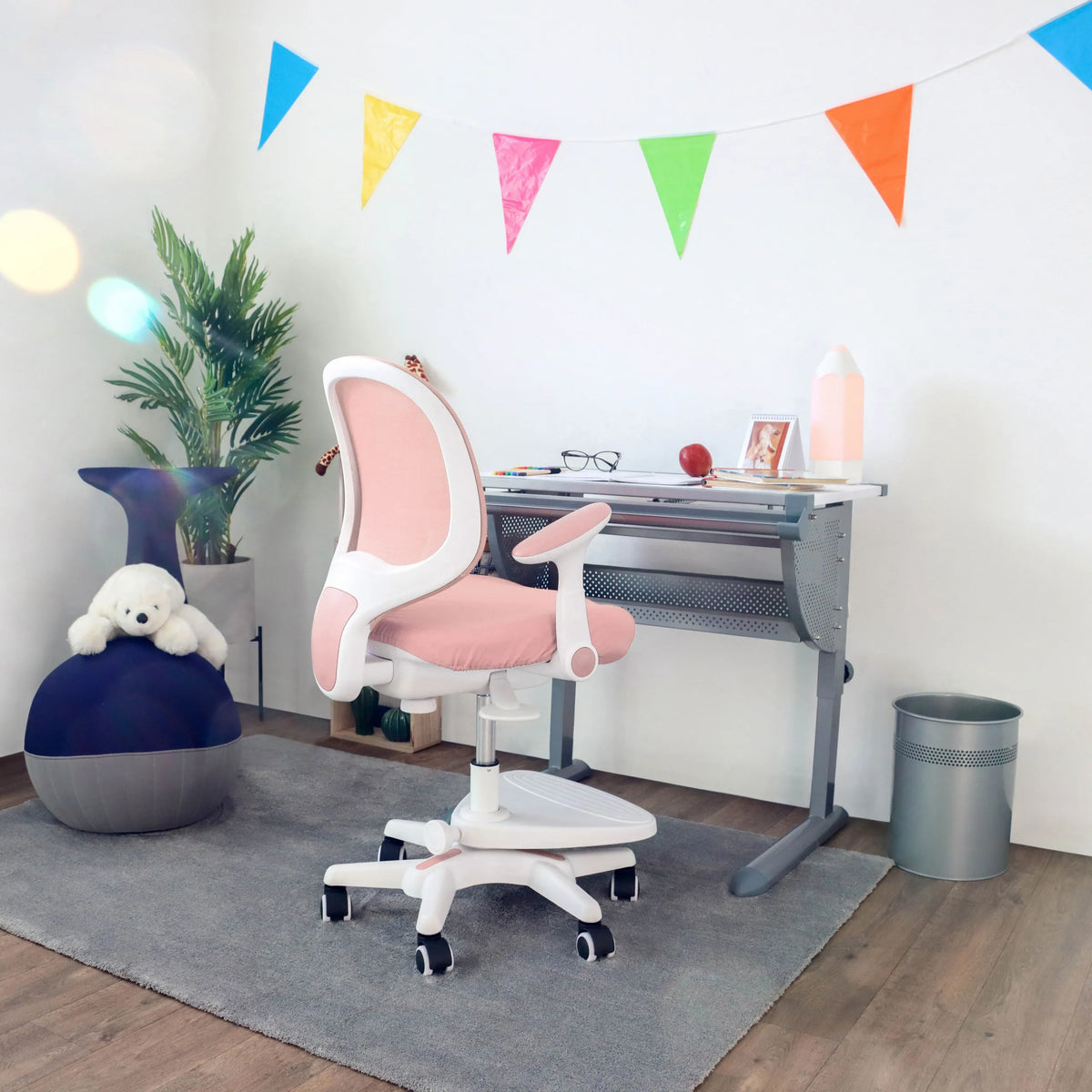 Rosa barnstol KID ERGO med vita armstöd och hjul vid ett skrivbord från hjh OFFICE