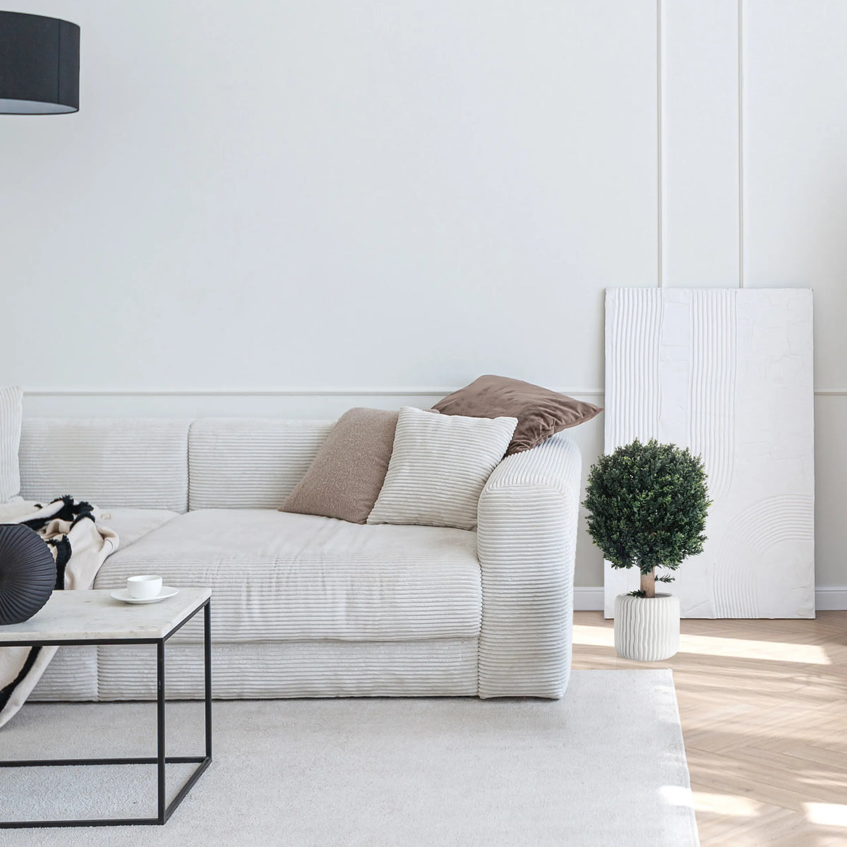 Grön Konstgjorda växter BUXUS i en vit ytterkruka bredvid en soffa från hjh OFFICE